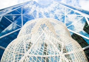 A striking low-angle view of a modern skyscraper and sculpture in Calgary, Alberta, Canada.
